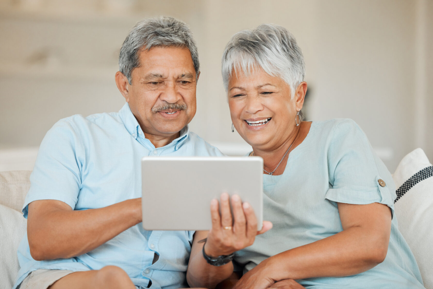 A husband and wife review information on a tablet.