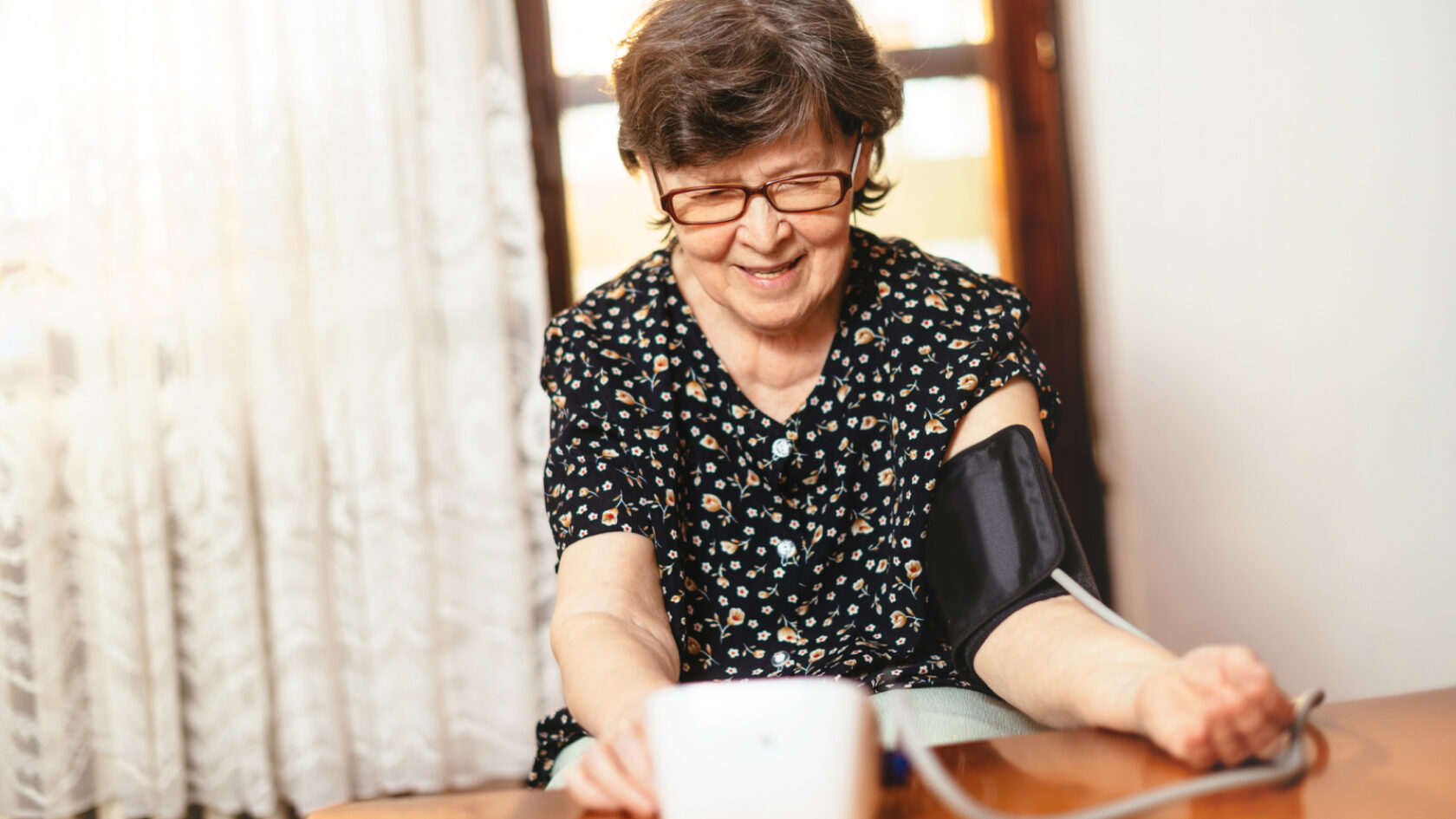 A woman takes her own blood pressure at home.