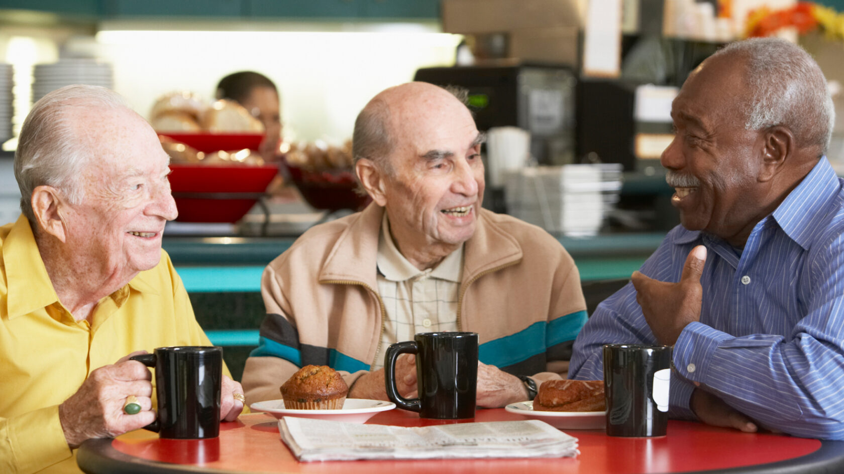 Three friends have a chat over cups of coffee.