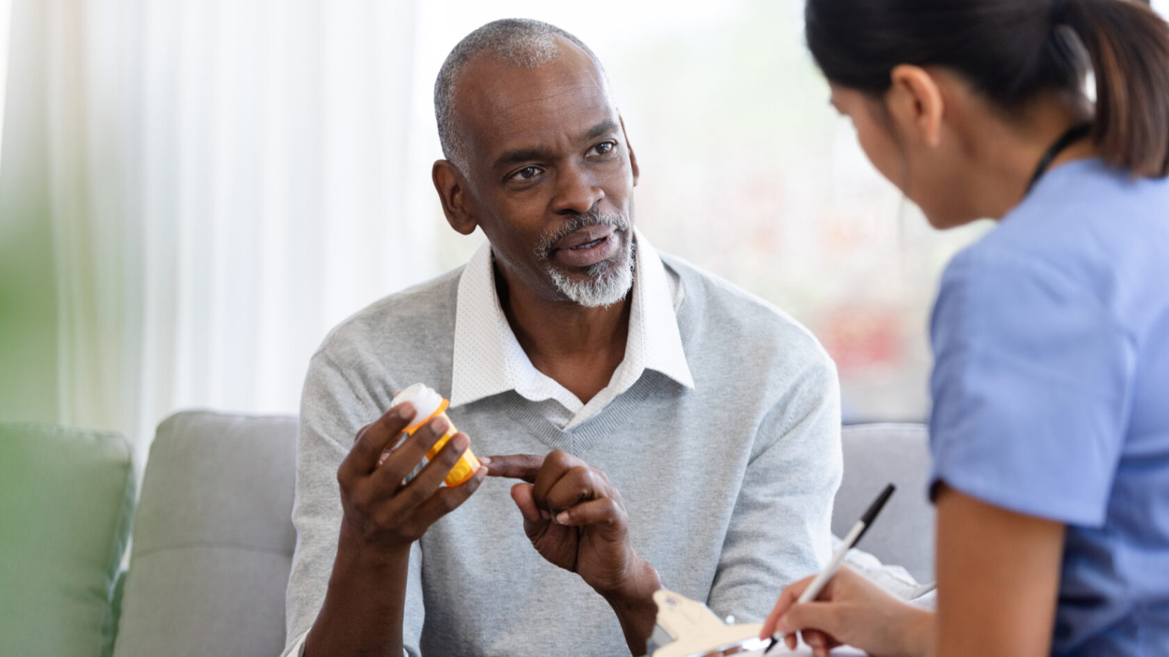 A man reviews his prescription information with a clinician.