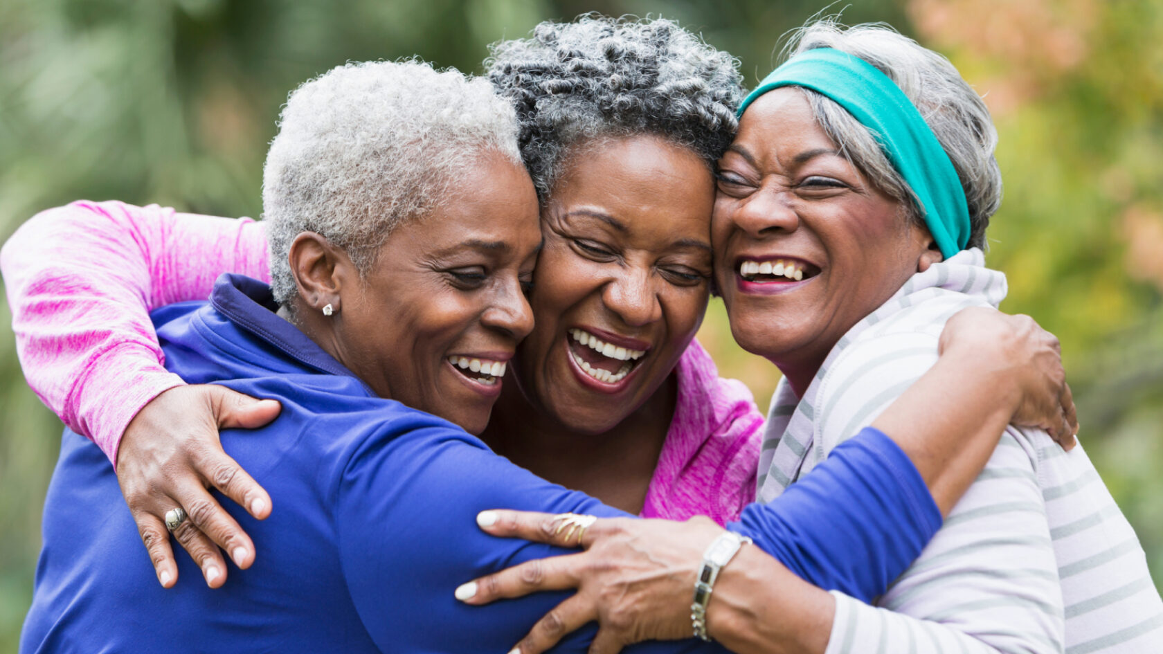 Three women share a group hug.