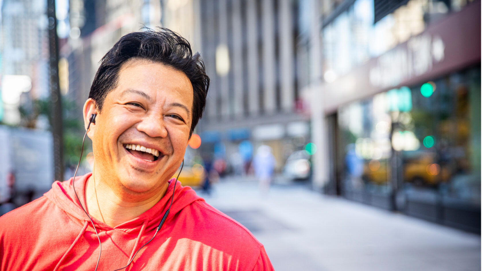 A man smiles as he walks down a city block.
