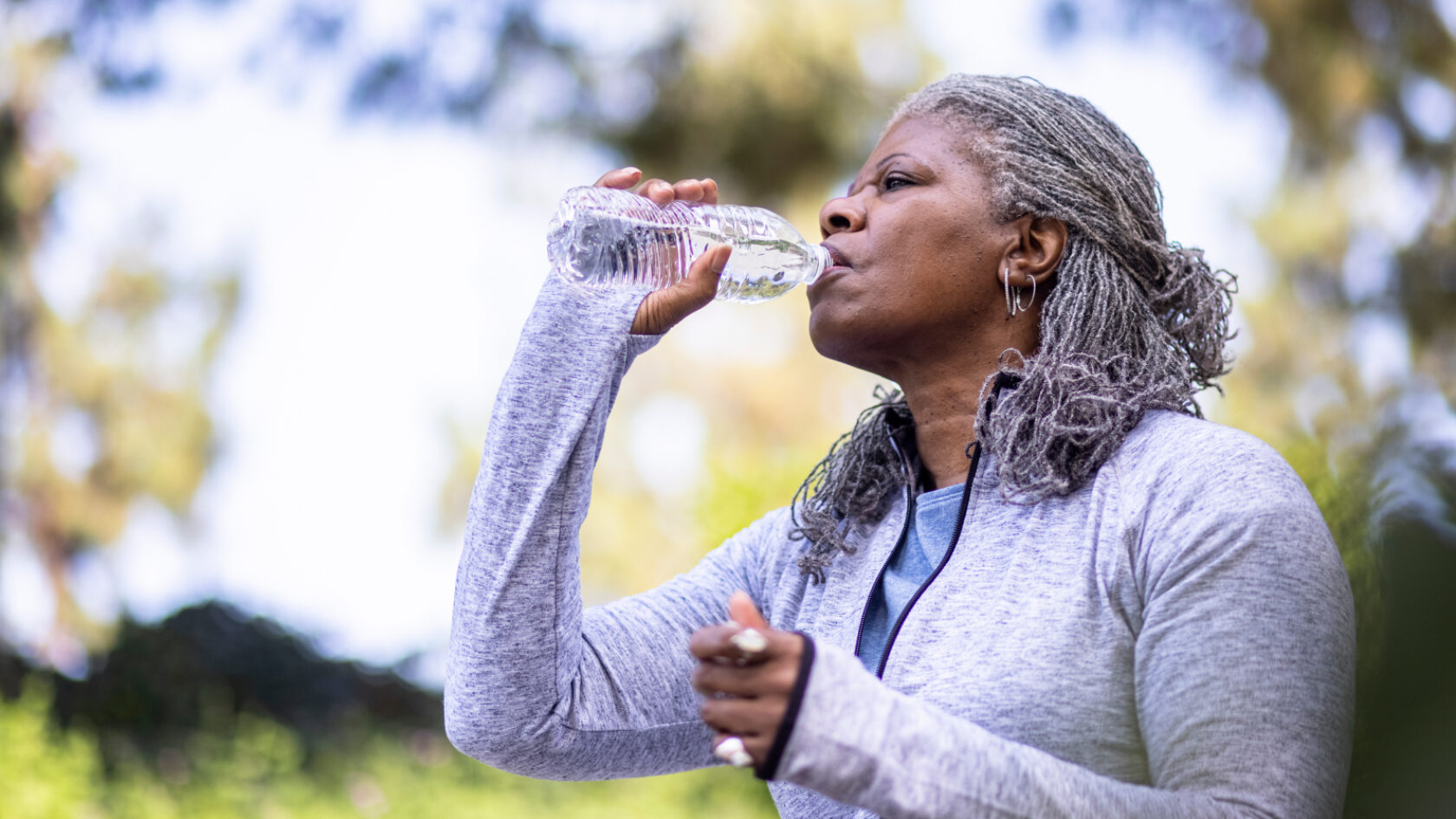 A woman stays hydrated while out exercising.
