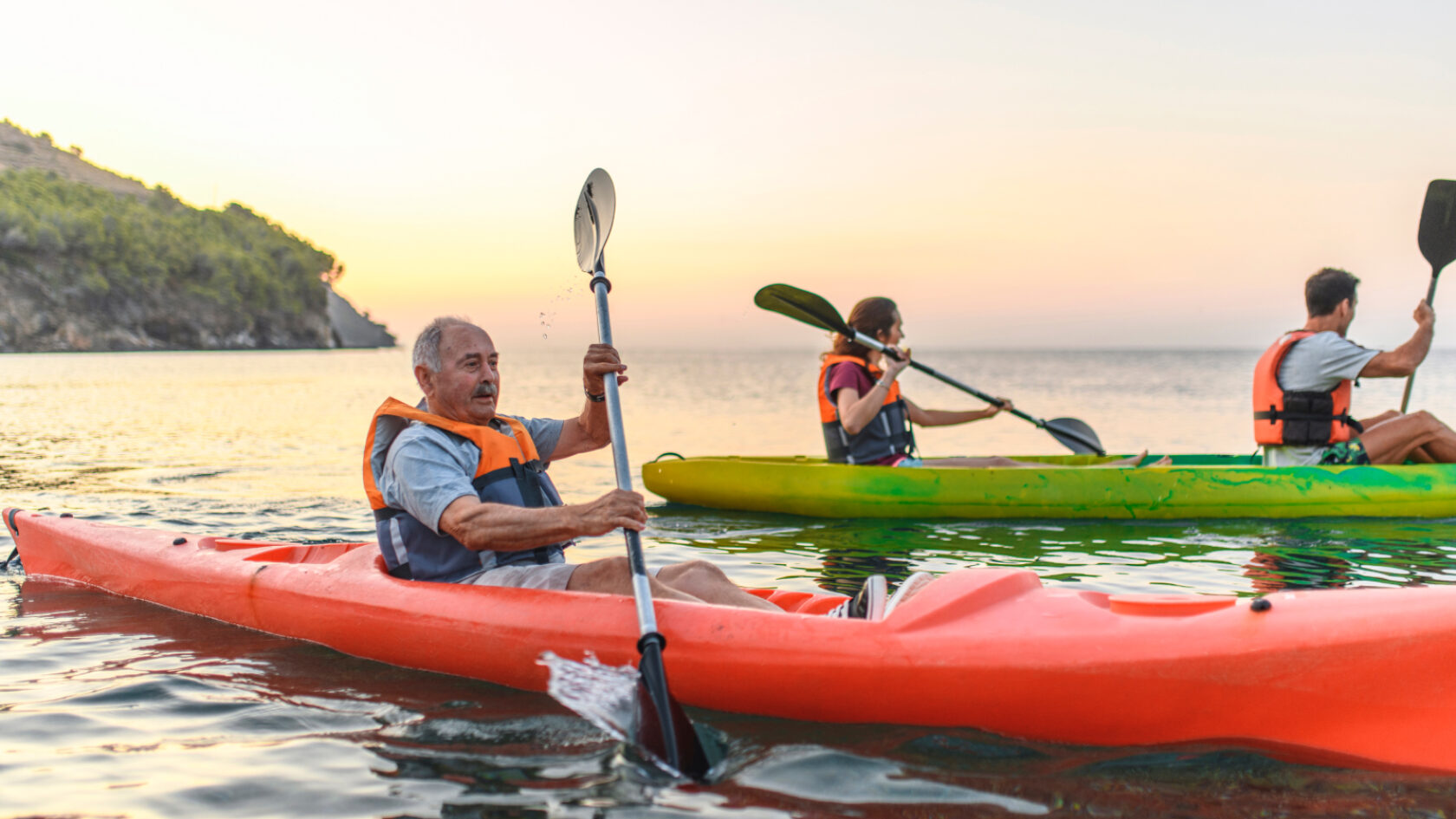 A man paddles his kayak while wearing a personal flotation device.