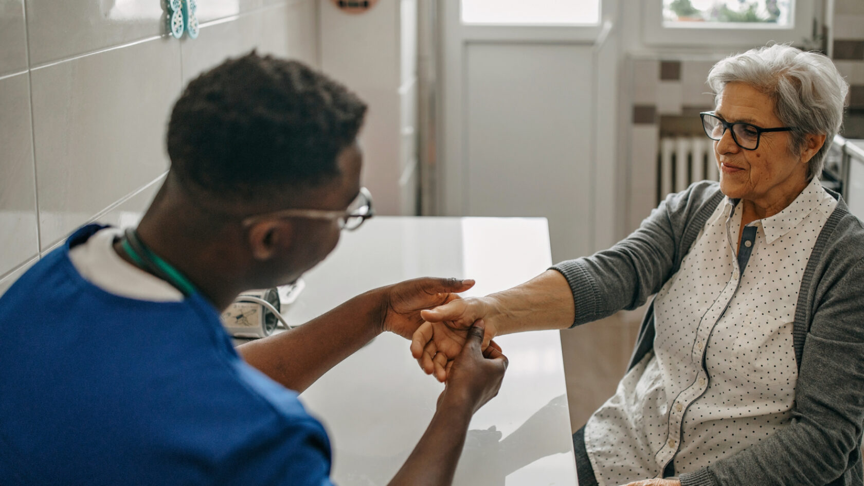 A clinician performs a medical evaluation on a woman's hand.