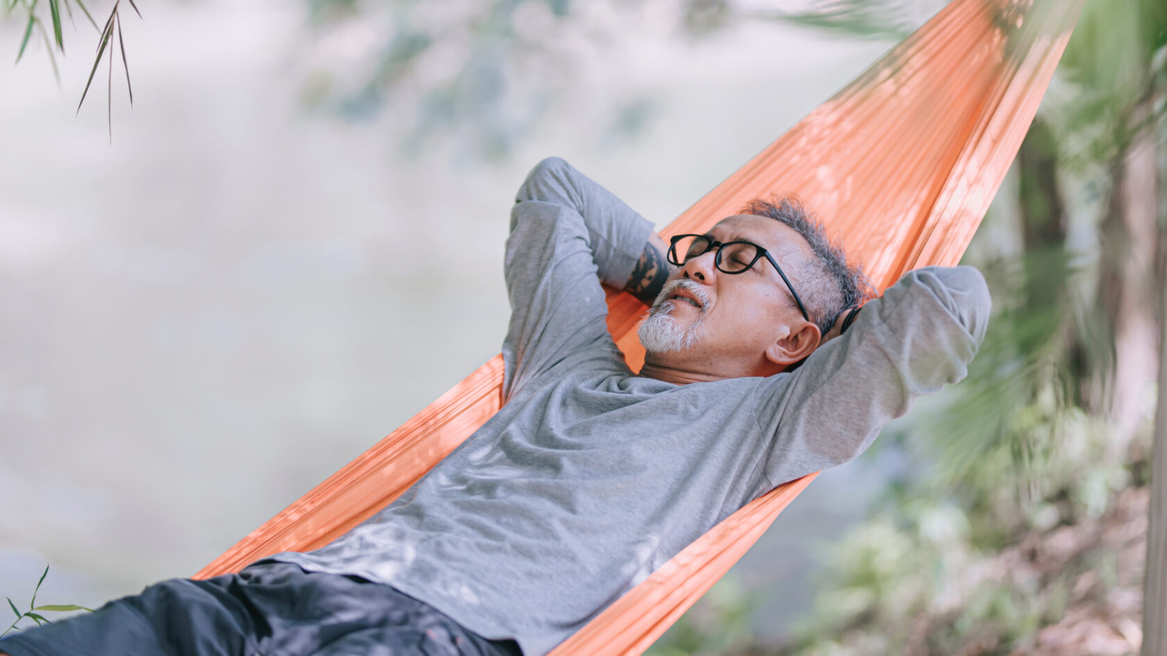 A man takes a nap on a hammock.