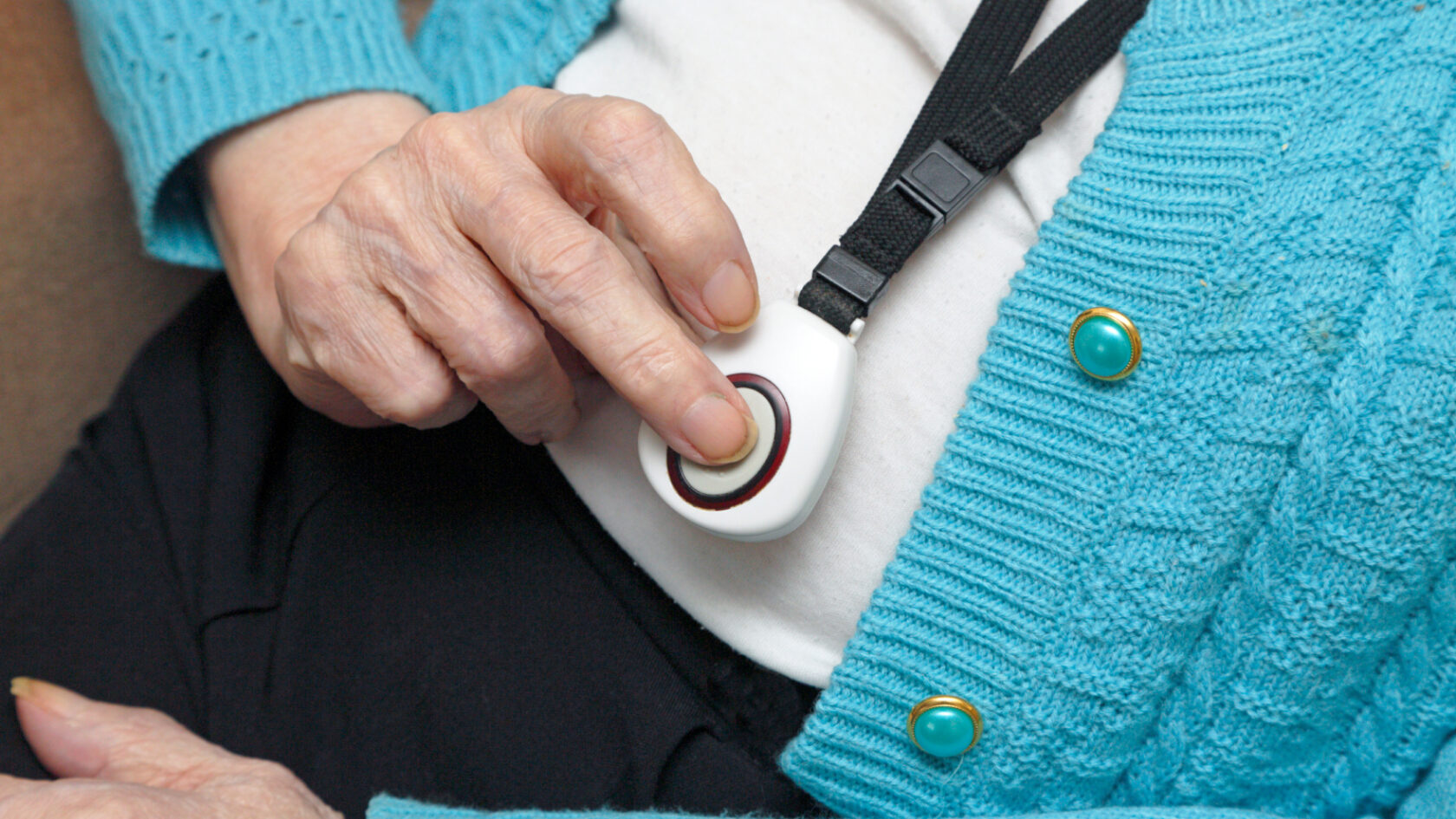 A person presses the button on a medical alert device.