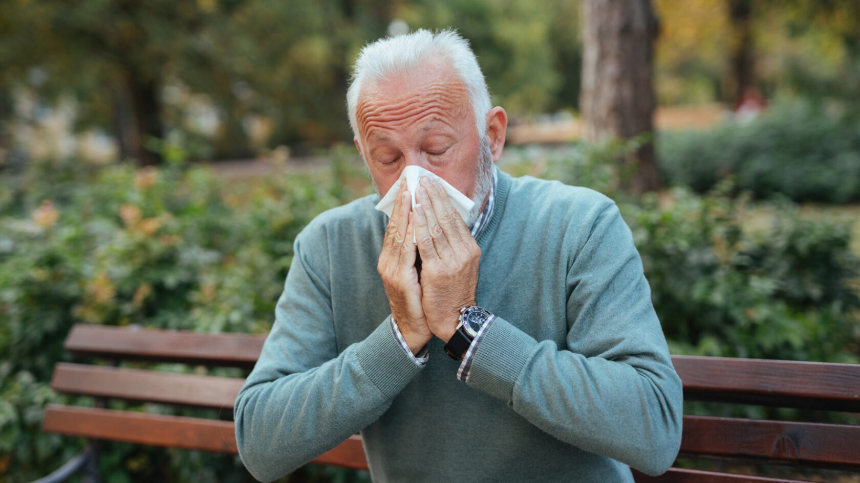 A man blows his nose into a tissue.