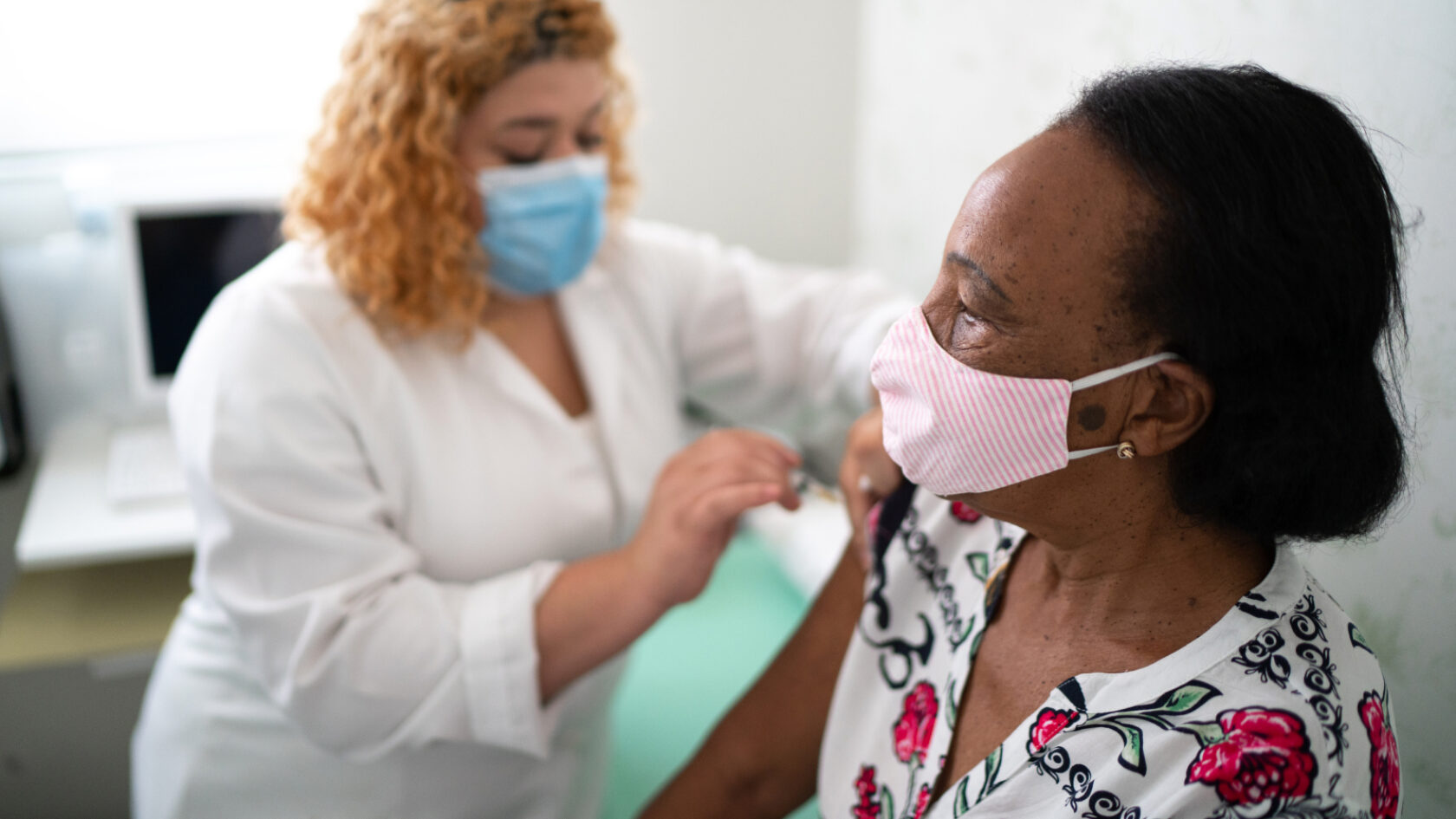 A clinician gives a patient a vaccination in a doctor's office